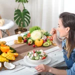 young-happy-woman-eating-salad-table.webp